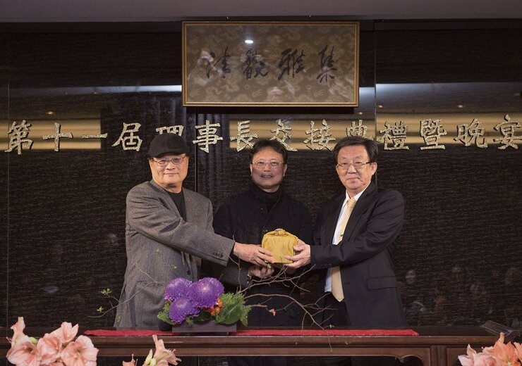 清翫雅集第11屆理事長翁明顯（右）在洪三雄（中）的監交下，從第十屆理事長潘文華（左）手中接下印信。