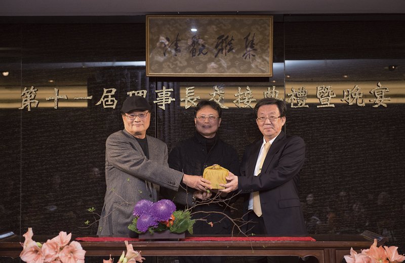 清翫雅集第11屆理事長翁明顯（右）在洪三雄（中）的監交下，從第十屆理事長潘文華（左）手中接下印信。
