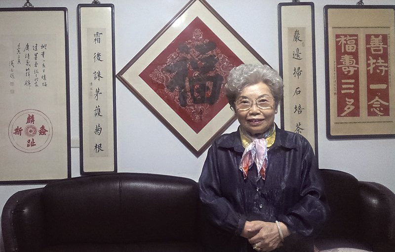 今年已高齡80有餘的諶德容和家中溥心畬字畫合影。