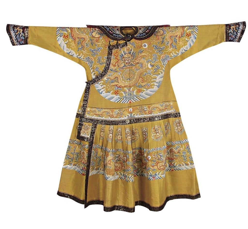 清〈黃紗納彩雲龍朝袍〉，瀋陽故宮藏。服裝有明顯的「減章」，如開襟處剪去「黻」章，應為設計或製作時省略。
