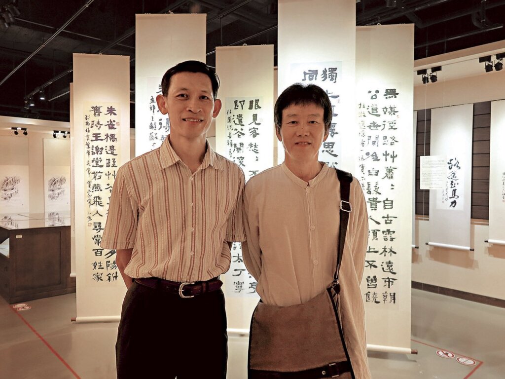 林業試驗所助理研究員徐健國（左）、前助理研究員王國財（右）於小魚〈五幅屏條〉（畫心染）前合影。