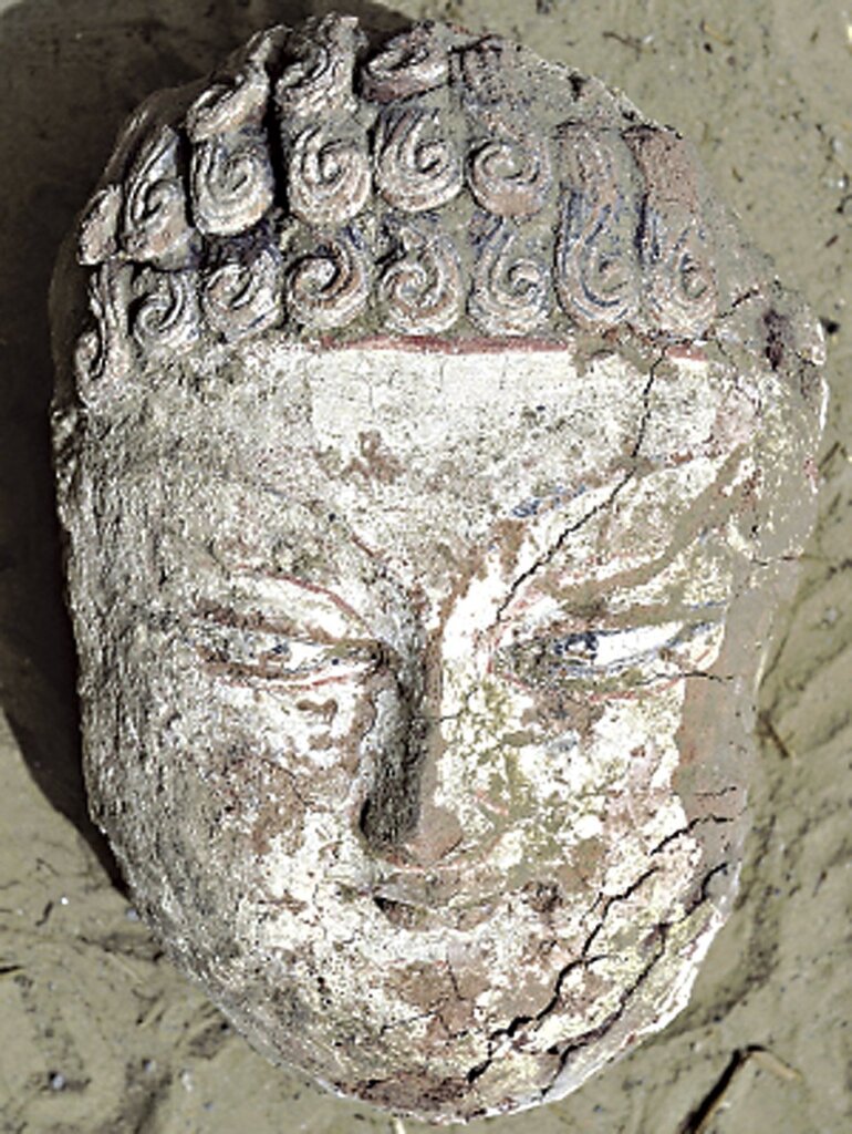 唐代泥塑彩繪佛頭殘件，達瑪溝托普魯克墩二號遺址出土，新疆策勒縣達瑪溝佛教遺址博物館藏。