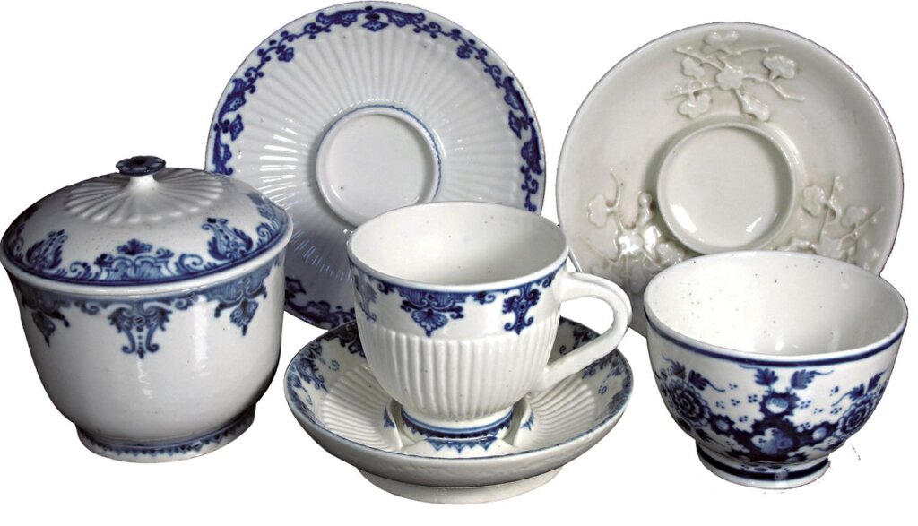 聖克婁餐瓷器皿：a（前排左一）約1730年〈青花垂帷紋蓋附糖罐（Pot á Sucre）〉，10×10×6.5公分。b（前排左二）約1717〜1722年〈青花垂帷紋杯碟組〉，杯6.9×7.2×3.8公分；碟3×11.6×7.5公分。c（後排左一）約1740年〈青花垂帷紋底碟〉，3.3×13.3×7.6公分。d（前排左三）約1740〜1760年〈青花洞石牡丹紋茶碗〉，6×8.4×4.5公分。e（後排左二）約1730〜1750年〈梅枝浮雕貼花底碟〉。軟質瓷器，台灣私人藏。