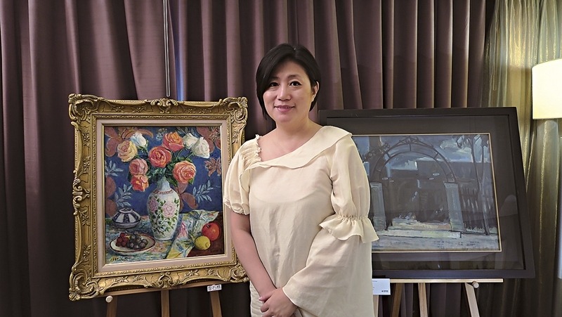 阿波羅畫廊總經理張凱迪攝於前輩藝術家作品前。左為只展不售的李石樵《玫瑰》、右為蕭如松《凌晨瓦窯場》。