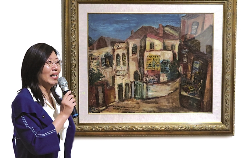 策展人台北市立美術館典藏組編審林育淳與其經手購藏的張萬傳〈鼓浪嶼風景〉。攝影／鄭婷婷。