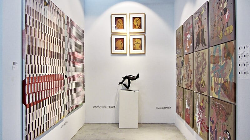 2015高雄藝術博覽會馬來西亞當代藝術特區一隅。 左牆：Saiful RAZMAN《Do not trust Anybody》．Enamel paint on canvas．183×146 cm．2015。 中間牆面：周春美《外來者》．綜合媒材．30×21 cm．2015。牆前為鄭元德的雕塑作品。 右牆：Ruzekki HARRIS《12生肖》系列．壓克力彩、油彩、畫布．單張66×66 cm．2015。