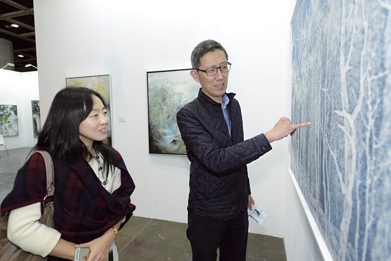 高士畫廊總經理張孟起在為參訪者解說藝術家吳珮華作品《白線的跳動系列之66》。