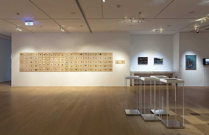 「凝光映語」展場，左牆為100件「鍾女士」系列，前方是可同時看見版與畫的裝置。