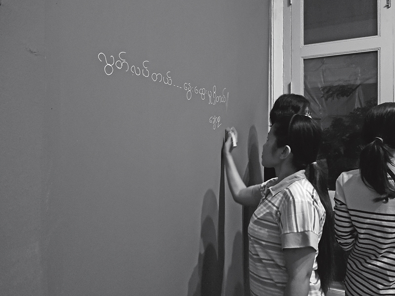 Chaw Su與Kyaw Moe在牆上書寫緬甸文作品名。(攝影/鄭文琦)