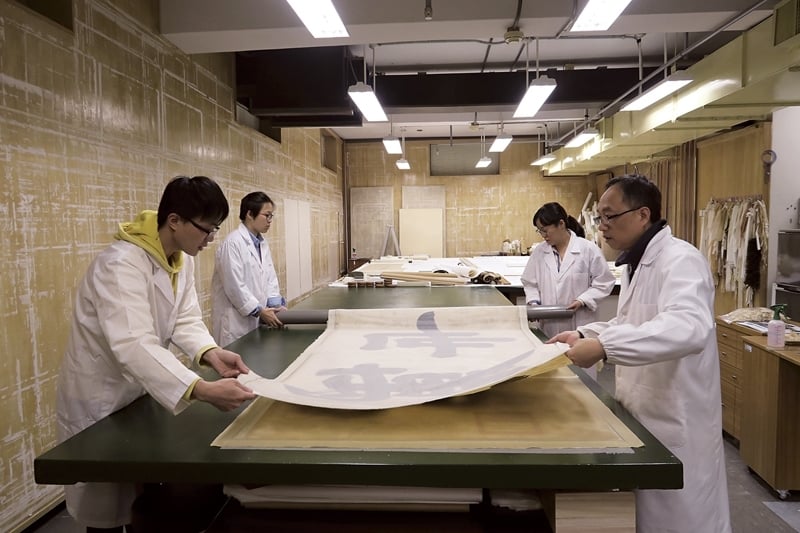 圖為故宮裱畫室的日常一景，修復師配合故宮展覽的時程，在展品亮相前先行檢查並進行必要修護。（洪順興提供）