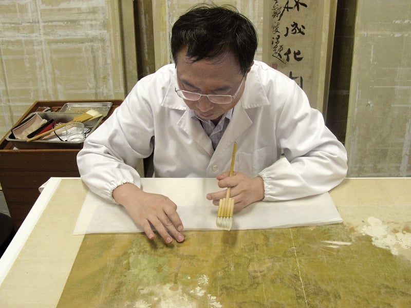 清代郎世寧〈錦春圖〉揭命紙的過程。「命紙」，緊貼於畫心後的一層紙，影響畫心壽命甚巨，至為關鍵。（洪順興提供）