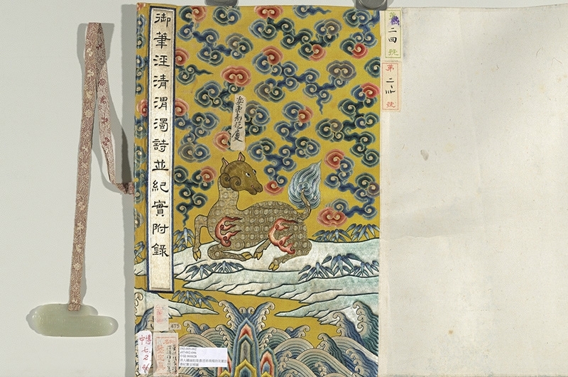 「乾隆品牌」：清〈清人繡線乾隆書涇清渭濁詩及董誥書紀實並補圖〉。明黃地五彩如意雲江崖海水天鹿織繡包首，手卷包首以織錦最多，少量緙絲，刺繡包首數量更少，可見其華麗與獨特性。圖片提供：國立故宮博物院