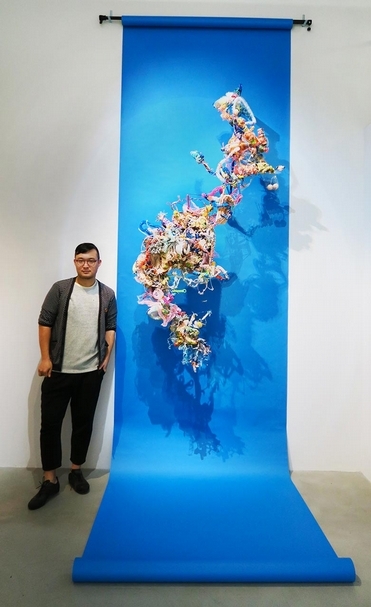 藝術家黃彥超與作品。《癱瘓．流量》．雕塑、塑料、現成物、丙烯、輕質土．212×48×117 cm．2017。攝影：楊椀茹