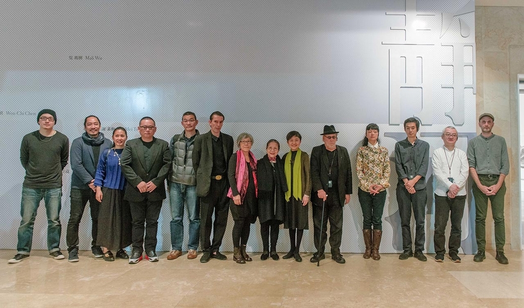 高雄市立美術館館長李玉玲（右起第6位）與參展藝術家合影；右起為澎葉生（Yannick Dauby）、須田悅弘（Yoshihiro Suda）、橋本雅也（Masaya Hashimoto）、柳美和（Miwa Yanagi）、科蘇思（Joseph Kosuth）；左起為Candy Bird、次仁札西．杰塘、蔡佳葳、陳文祺、石晉華；左起第7、8位為吳瑪悧、林麗珍。圖片提供：高雄市立美術館
