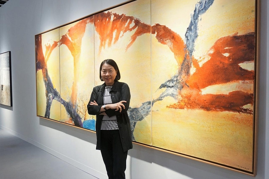 耿畫廊本屆豐收，所有作品在開展兩小時幾乎售罄。參展本屆香港巴塞爾的頂級作品之一：定價2,400萬美元，趙無極1989-90年的作品《12.89-02.90》，也已有重要藏家鎖定欲購藏。此為耿畫廊負責人耿桂英與此幅難得的四連屏抽象大作合影。（攝影／林亞偉）