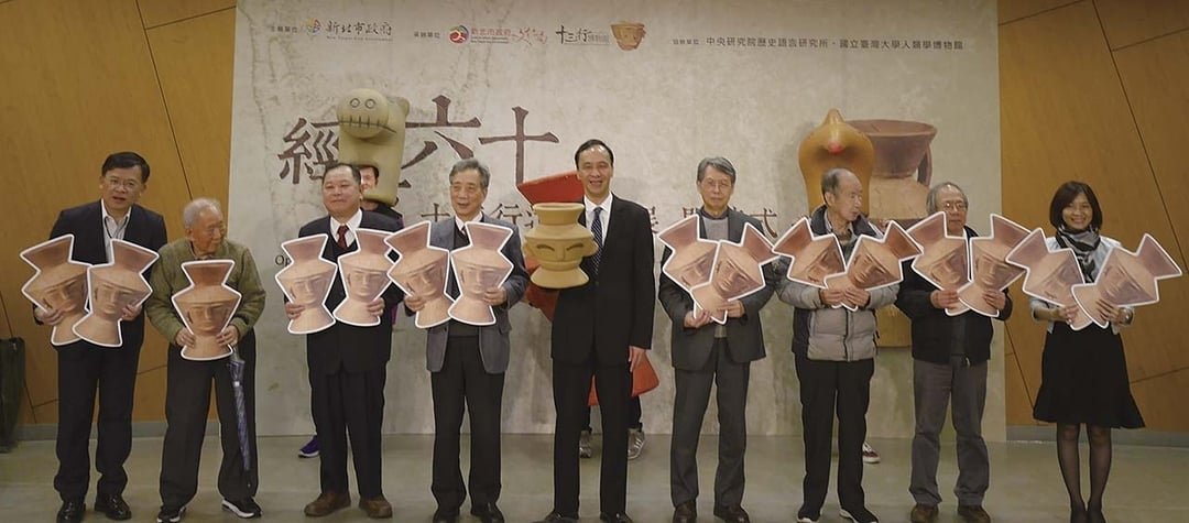 新北市長朱立倫（中）、學者黃光男（左四）、文化部文化資產局副局長邱建發（左三）、中央研究院歷史語言研究所所長王明珂（右四）、考古學者劉益昌（右二）及多位重要考古學者手持「人面陶罐」板共同揭幕。圖︱新北市立十三行博物館