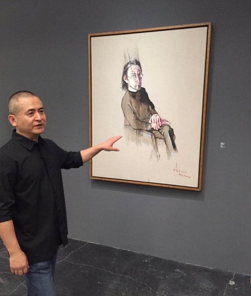 曾梵志在2016年UCCA「散步」大展，與畫作合影。畫作內的肖像，即為香格納畫廊創辦人何浦林（Lorenz）。（攝影／簡秀枝）