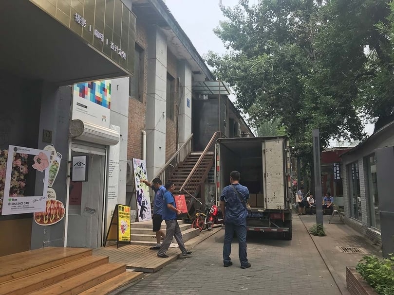 將飲用水裝箱收繳，遠景為工商局人員在詢問為活動提供空間的友人。（卞卡提供）