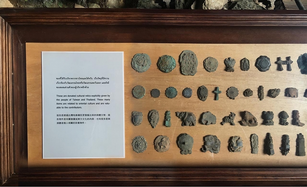 第二個玻璃櫃置放泰國朋友在工作坊所提供具泰國文化特色的物件，後製成類似化石質感的偽文物。（涂維政提供）
