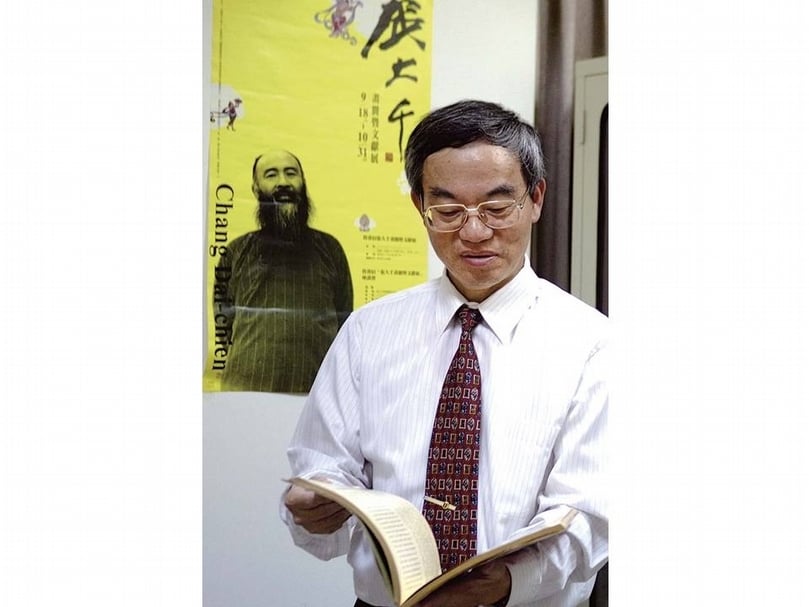 吳文隆在他的書房，背後是2010年臺北舊香居「張大千畫冊暨文獻展」海報。（攝影╱藍玉琦）