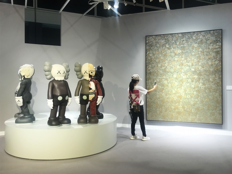 佳士得拍賣預展現場，「離心力專場」作品相當吸引年輕族群拍照，左為KAWS的《同伴》系列，右為以516萬5千港元成交價的梁遠葦《無題 2013.17》，在本季締造個人拍賣紀錄。（本刊資料室）