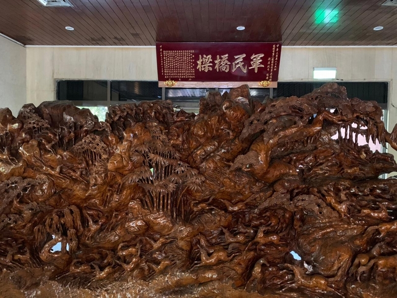 國軍英雄館內「軍民橋樑」的匾額,與前方一座樹瘤屏風在川堂。(攝影/劉星佑)