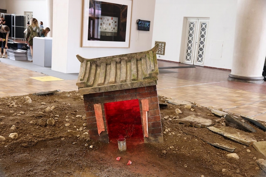 台灣國家館「寶島浮沉」在五公尺見方的展位上裝置遺址場景，設置一座台灣常見的土地公小廟及大量的廢土。（攝影／郭唐菱）