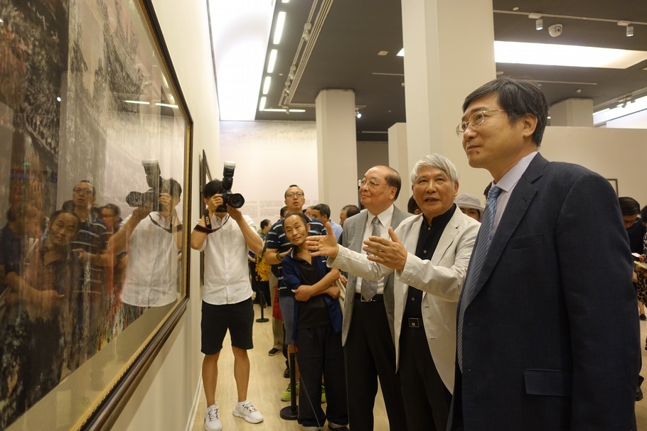 江明賢向文化和旅游部副部長張旭（前一）及文化台灣基金會榮譽董事長洪孟啓闡述創作理念。