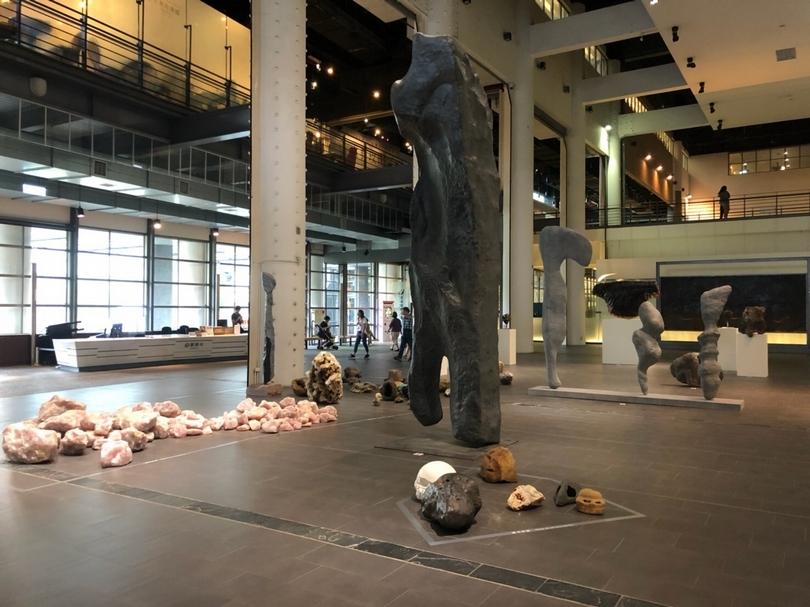 王思順的裝置作品《啟示》位於國美館入口大廳，展出藝術家持續從世界各地收集而來、近似人類形象的石頭。藉此喻為有著不同族類與身分，以及不同的歷史和未來的交會關係。（攝影／嚴瀟瀟）