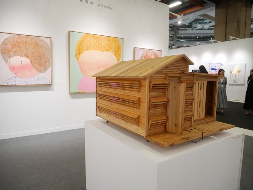 尊彩藝術中心展位蕭有志的「耕讀小屋」系列，後為羅喬綾的繪畫系列作品。（本刊資料室）