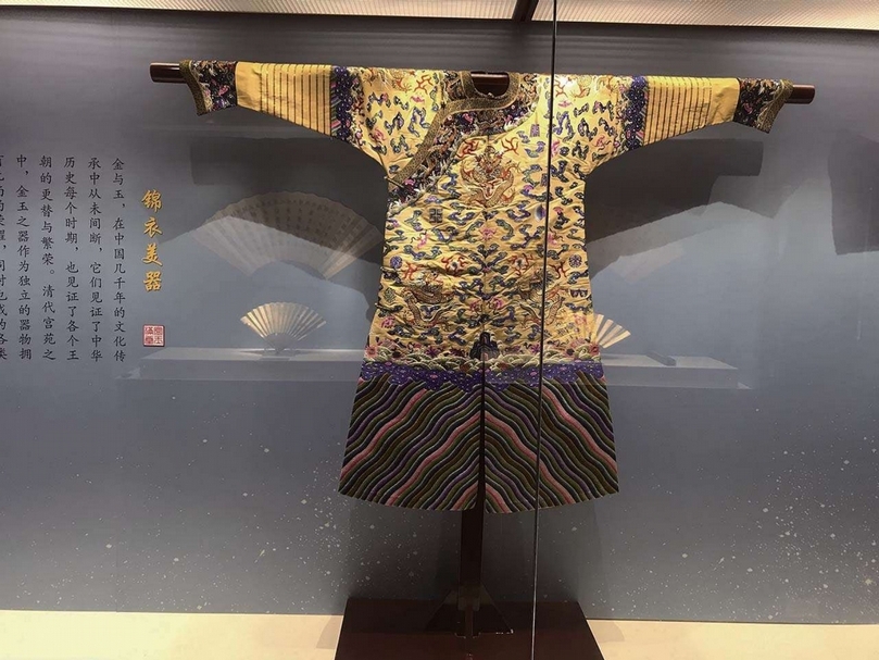 清《明黃江綢平金彩繡金龍棉袍》 身長116公分，腰寬58公分，下擺寬73公分，袖長79公分。龍袍圓領，大襟右衽，馬蹄袖，裾四開，直身式袍。領、袖邊鑲飾石青色團龍雜寶織金緞。龍袍面料為明黃江綢，彩繡雲金龍、暗八仙、十二章、海水江崖等紋飾。綴銅鎏金鏨花扣四枚。（劉曉晨提供）