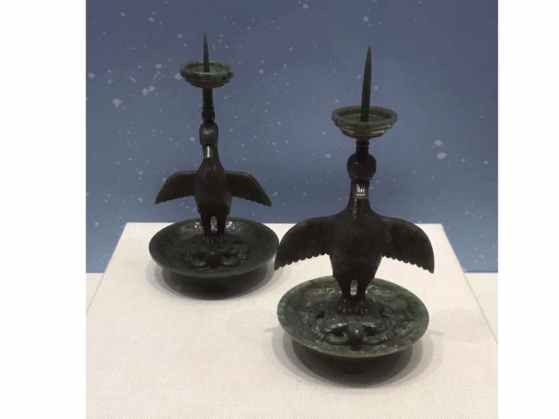 清《碧玉鳧形燭台》一對 高23.5公分。此燭台用碧玉製成。鳧指野鴨。燭台用圓雕和浮雕手法刻成，雕工細膩，圓盤深腹，外為蓮瓣紋，龜爬於圓盤上，龜首略向上抬，四肢伸出殼外貼於圓盤上，龜下盤蛇，龜背上站立一鳧，鳧為展翅狀，頭向下微低，口微張開，鳧的羽毛及頭腳均用浮雕手法雕刻而成。鳧頭頂燭台，燭台為圓雕倒立狀樓梯磴狀，燭台底部為弦紋狀，燭台上有燭。（劉曉晨提供）