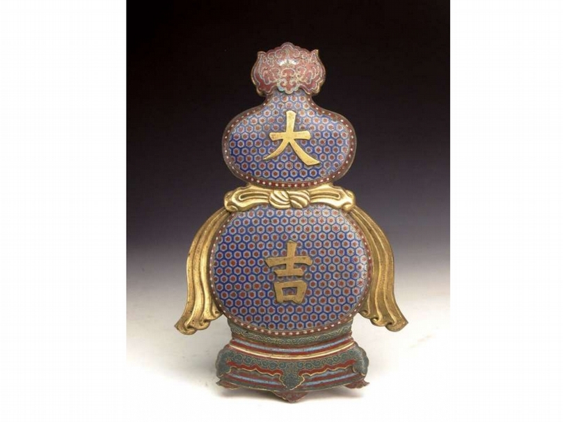 清《掐絲琺瑯大吉葫蘆掛屏》 銅胎掐絲琺瑯製。全高39.2公分。該掛屏呈傳統葫蘆之形，為上小下大兩個橢圓，葫蘆底部為仿製的低座，表面以深藍色琺瑯為地，滿飾六邊形紅色鑲灰邊錦紋，邊緣為深紅色邊，上飾白色乳釘紋，上、下腹部中心分別製鎏金楷書「大」、「吉」，束腰部位裝飾有鎏金飄帶。葫蘆口部為紅色蝙蝠如意頭紋，底座為紅、藍、金色條狀裝飾及綠色座托，座托表面滿卷草花紋，下部裝飾有如意頭形狀。（劉曉晨提供）