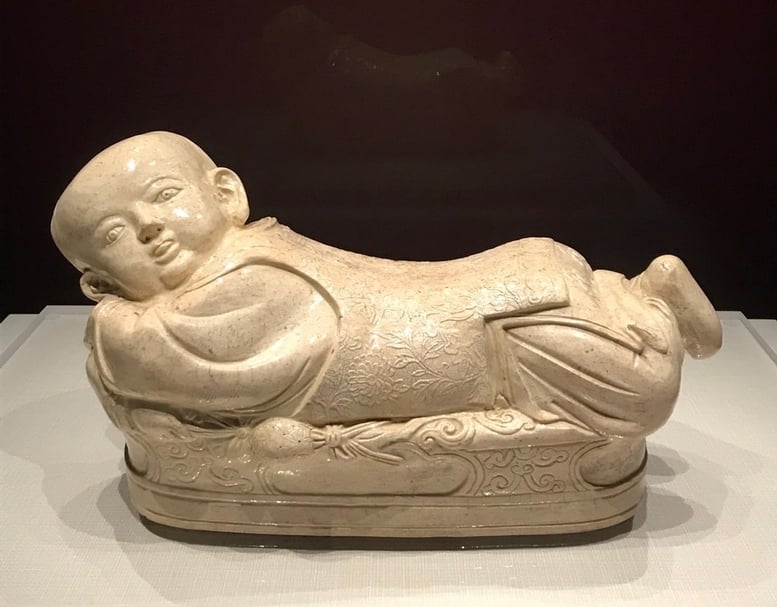 故宮南院「人氣國寶展」中的北宋至金《白瓷嬰兒枕》，模樣憨傻可愛。（攝影／藍玉琦）