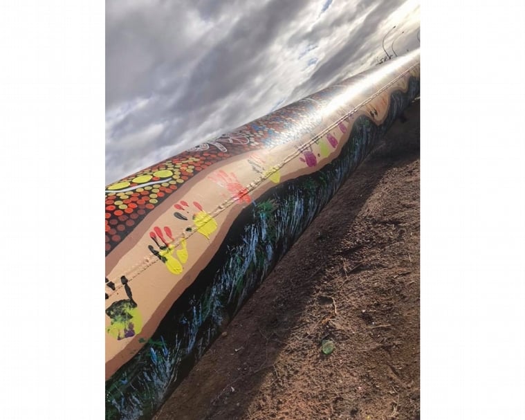 奧古斯塔港原住民族藝術團體 Wulla Designs的三位藝術家Leah Brown、Jasmine Brown和Candace Taylor推出作品《地海相遇》，將一幅連繋著祖靈、大自然和人類生命的畫面，覆蓋著由殖民政府布置橫躺於路上的輸水管——箇中反差，折射出某種「原住民精神價值」vs「殖民者物質治理」彼此互異的追求取向。（攝影／ Leah Brown）