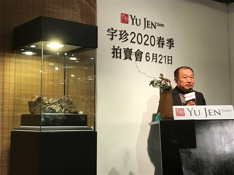 宇珍國際藝術董事長郭亨政於2020春拍記者會致詞。左方為「明德惟馨－亞洲重要私人沉香珍藏」專場拍品：仙山妙境〈越南芽莊沉水浮棋楠〉，長27公分，重685克、長27公分，重649克，預估價：1980萬至2500萬元新臺幣。（攝影／藍玉琦）