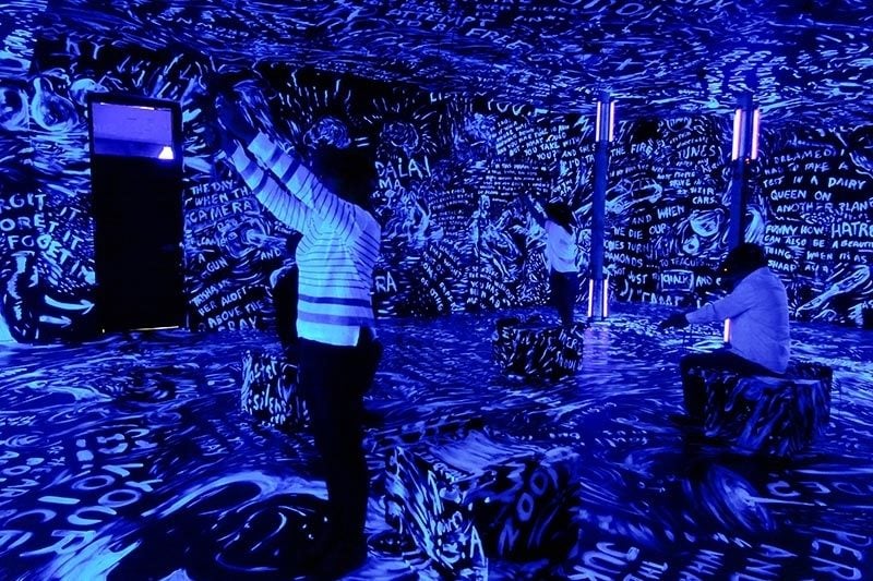 播放VR作品《沙中的房間》時,觀者進入展場時看到的現實空間,在展場中會先看到合作藝術家蘿瑞安德森(Laurie Anderson)在牆上的塗鴉創作。圖片提供:藝術家黃心健