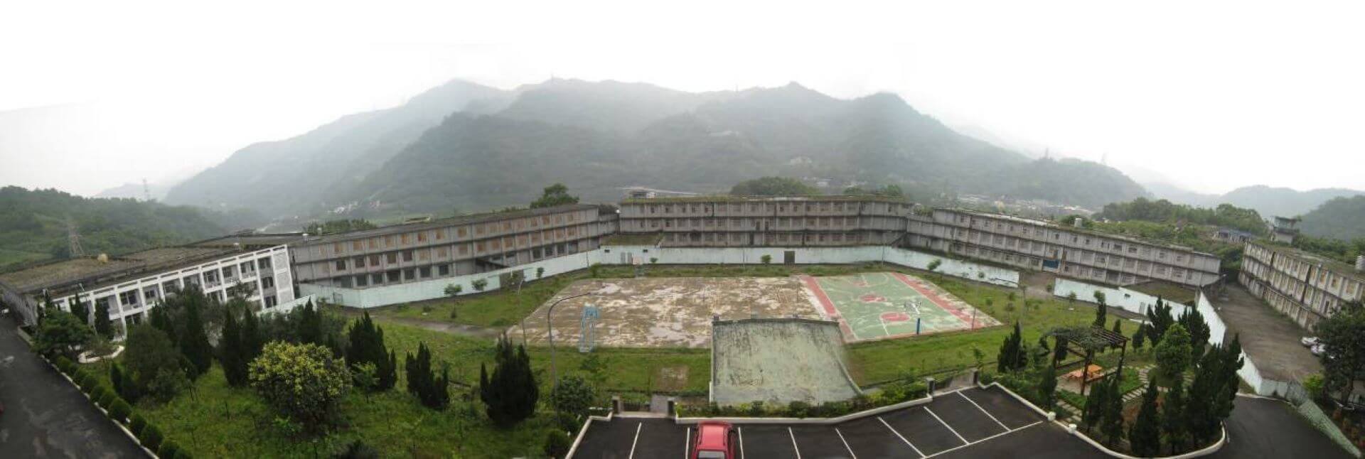 坪林山莊舍房區全景，操場前面至善樓、弘道樓、行仁樓及右後方的進德樓即是早期關犯人的房舍。（資料來源：《97臺北縣文化景觀普查計畫成果報告書》）