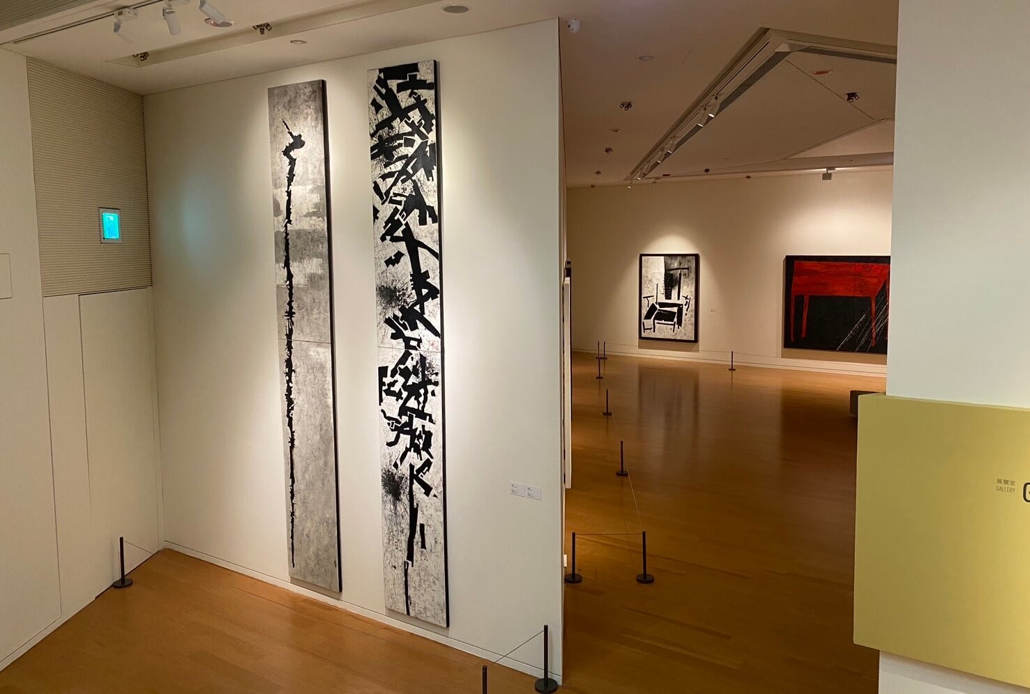 展場空間，前景兩件作品：（左）王懷慶《鶴頭杖》，2004，油彩畫布，400×60公分，私人收藏；（右）王懷慶《連環棍》，2004，油彩畫布，400×60公分，私人收藏。（攝影／朱佑霖）
