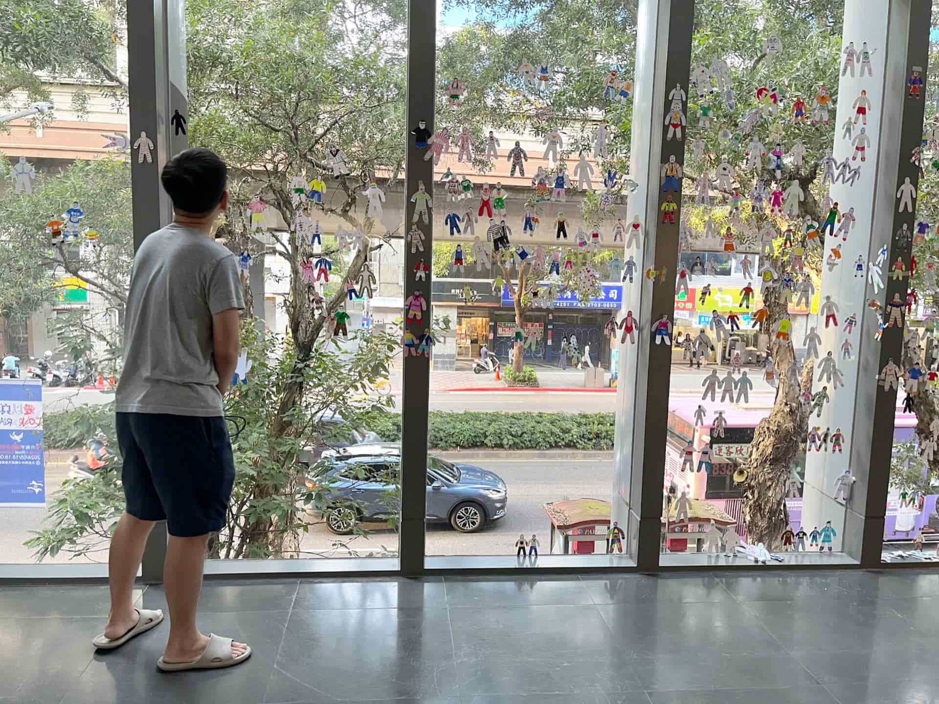 張立人端詳著眾多不知名、不知何方觀眾自由創作的小紙偶。5月16日。（攝影／謝鎮逸）