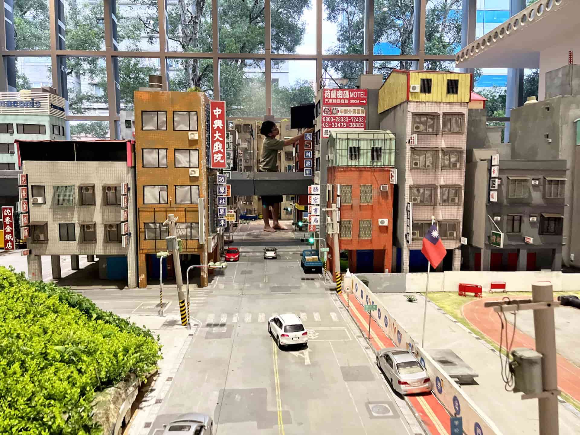 巨大化的張立人在城市場景模型中安裝「電視看板」。4月30日。（攝影／謝鎮逸）