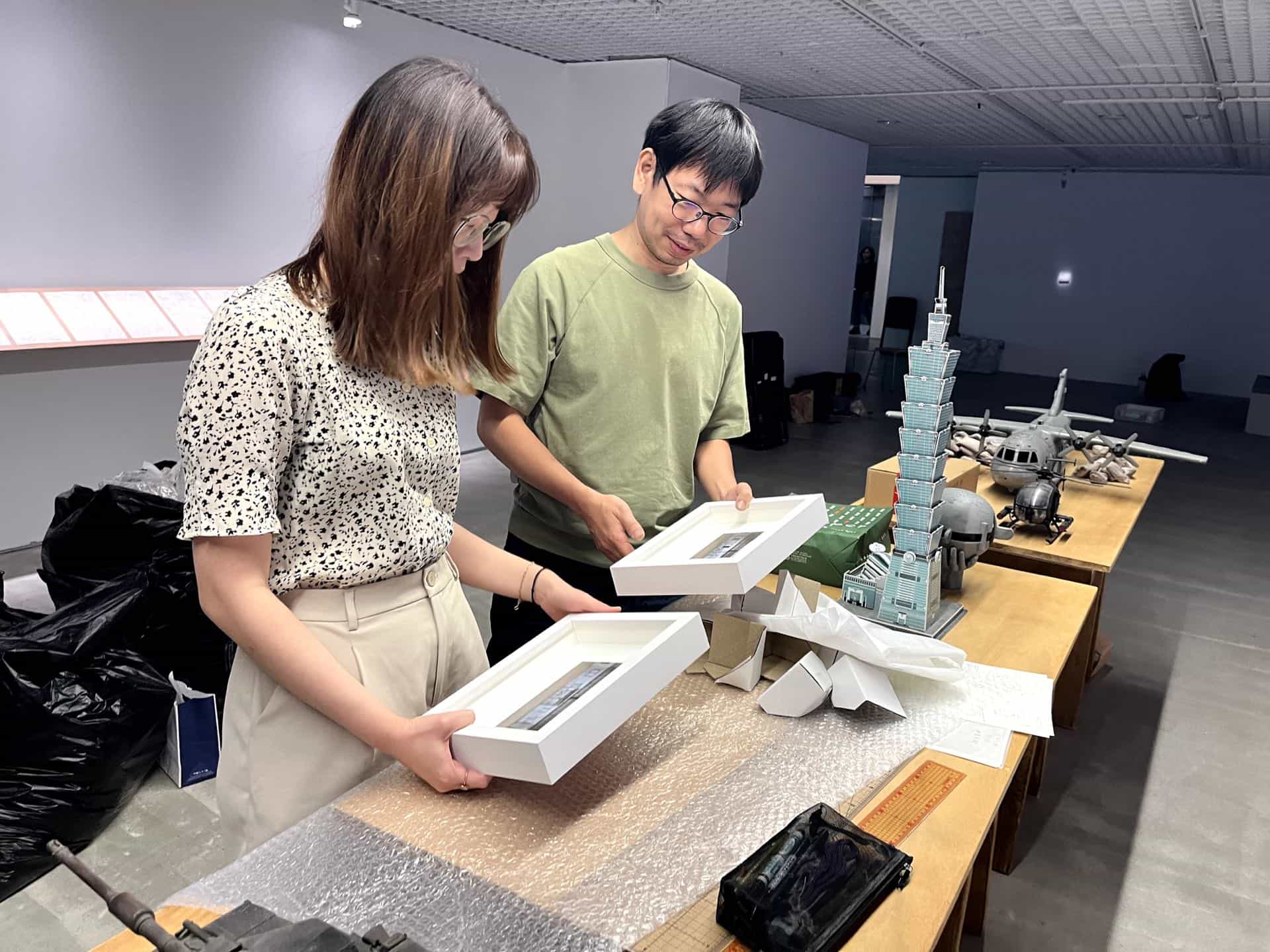 張立人與館員依盈開箱剛到手的兩張《學甲工廠照片》錶框成品。4月30日。（攝影／謝鎮逸）
