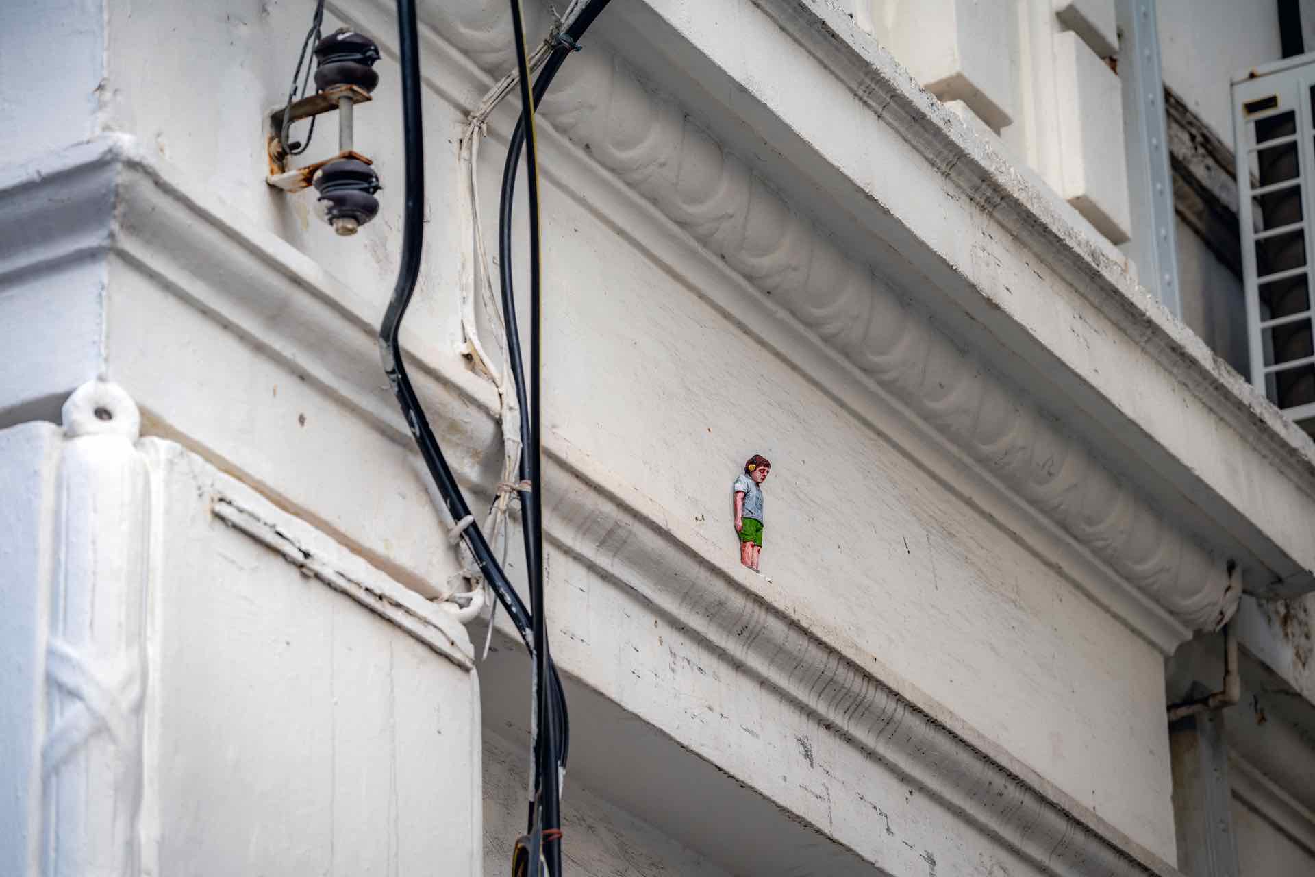 藝術家伊薩克（Isaac Cordal）的「水泥日食」（Cement Eclipses）在多個建物高處設置俯覽街巷的小型水泥雕塑人偶。（喬治市藝術節提供）