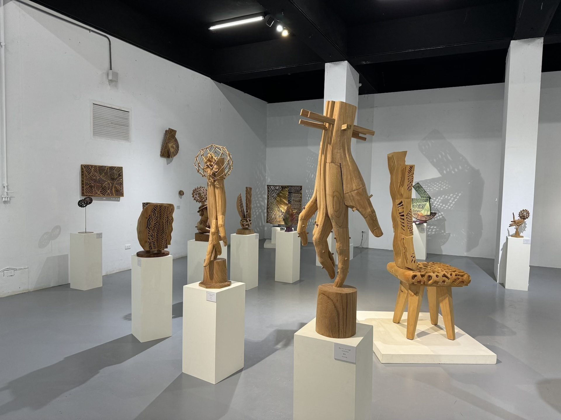 透過觀察展覽現場展出之「手」系列創作，可見作品以軸心為基礎，木片、木塊交疊構成手部骨架，並以契子固定內部結構，展現精密的木雕技法。圖為「竹田光幸 × 竹田智美 雙人展」展出現場。（攝影／李京樺）