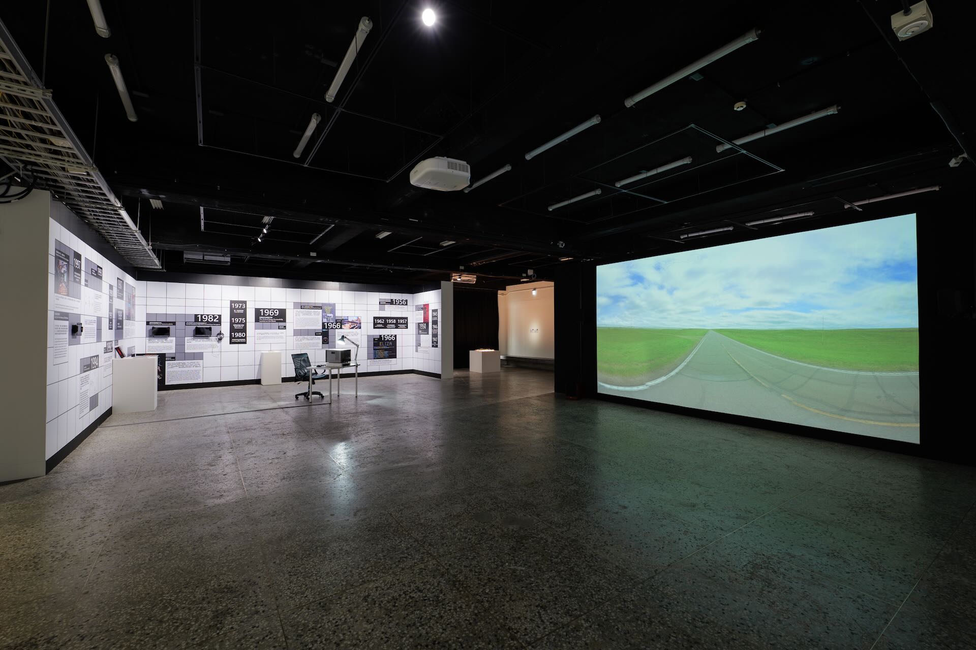 「2024未來媒體藝術節——奇異點」第一章「流動的錨點」展場照，左為自牧文化爬梳AI發展歷程的年表，右為袁廣鳴作品《扁平世界 》。圖／C-LAB提供