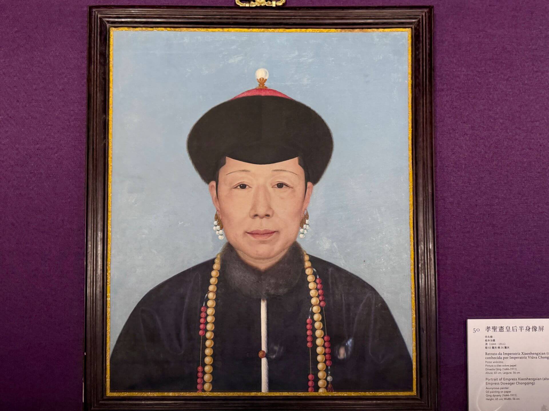 畫中孝聖憲皇太后身穿藍色常服，頭戴吉服冠，表情肅穆溫和。清《孝聖憲皇后半身像屏》，紙本油畫，65×56公分，北京故宮博物院藏。（攝影／朱佑霖）