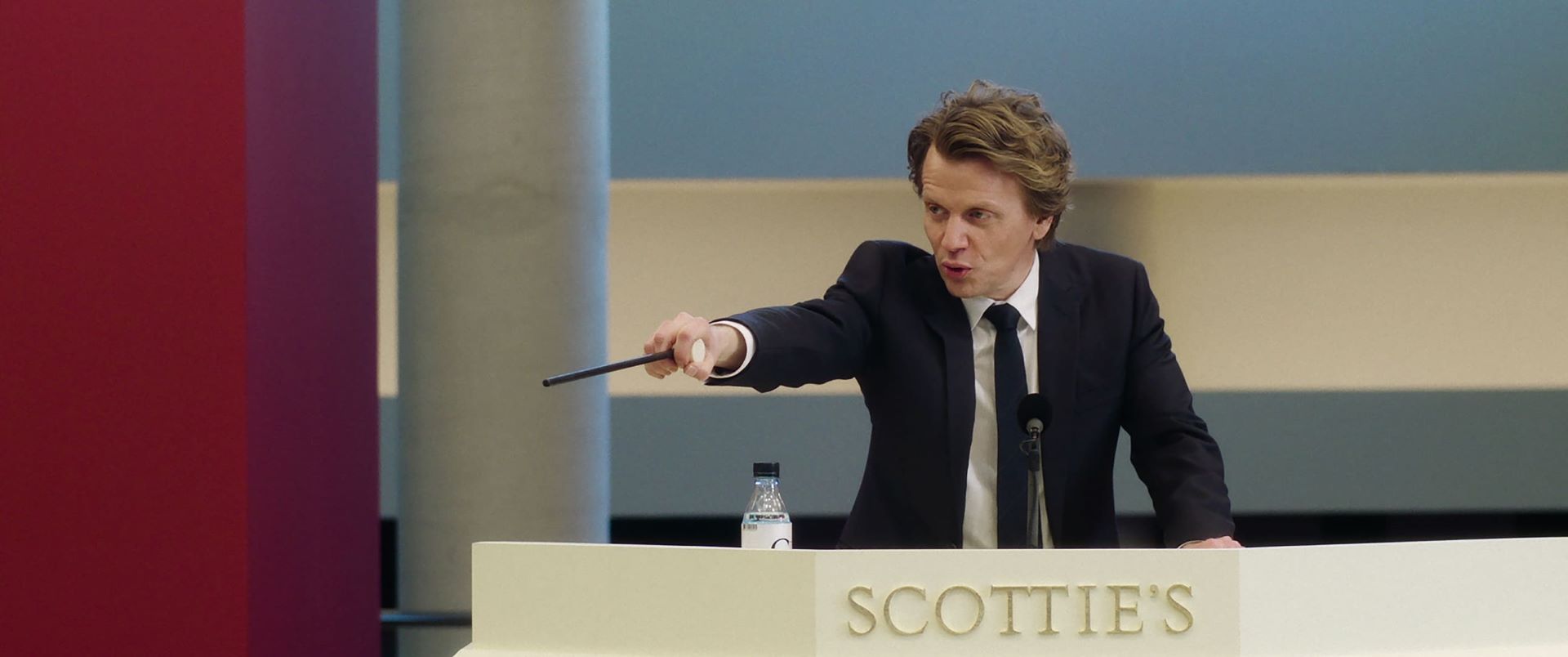 飾演拍賣師湯瑪斯．塞杜克斯（Thomas Seydoux），《秋日陽光》以當時1,168萬英鎊（約2,168萬美元）的高價落槌。（電影《逆轉拍賣師》，佳映娛樂提供）