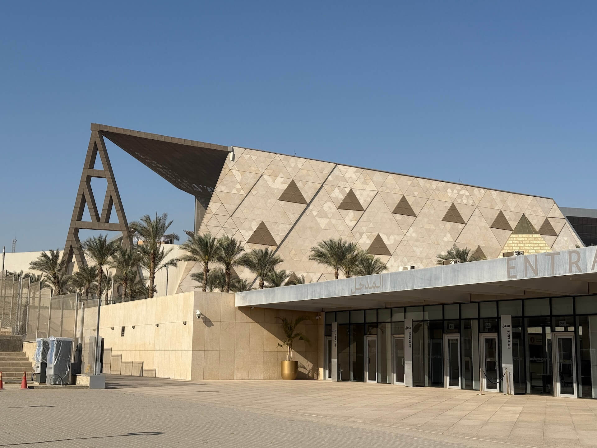 大埃及博物館外第一道入口，建築延伸出的三角形屋簷直指吉薩基字塔群。（攝影／朱佑霖）