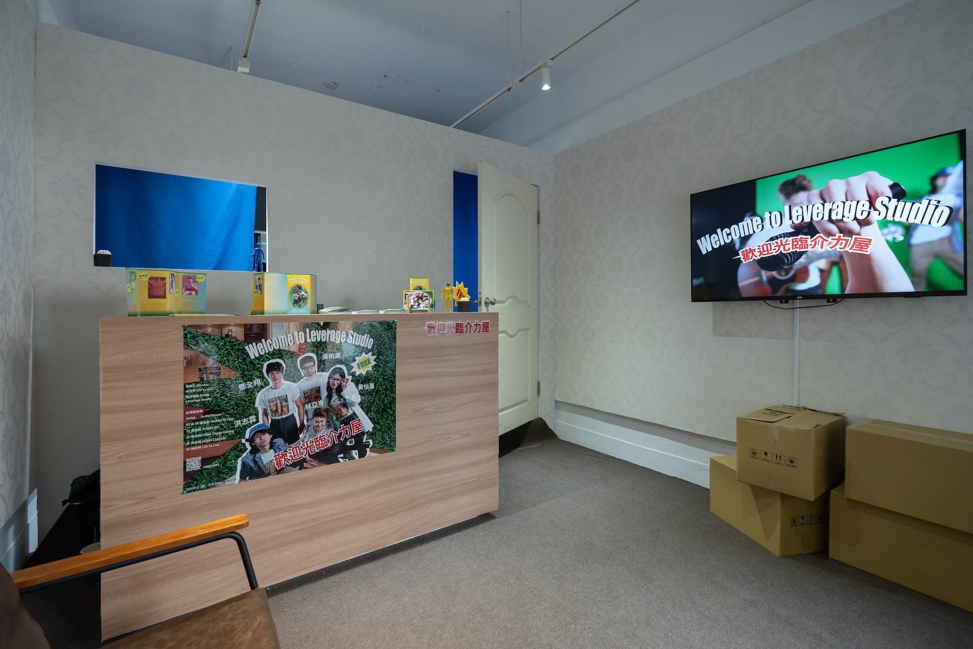 展覽入口處以台灣常見的壁貼、沙發、壁掛電視和櫃台，營造出如萬華街頭店面般的半居家氛圍。電視螢幕輪播「租客」——藝術家們的偽訪談影片。（攝影／劉耀鈞，介力屋提供）