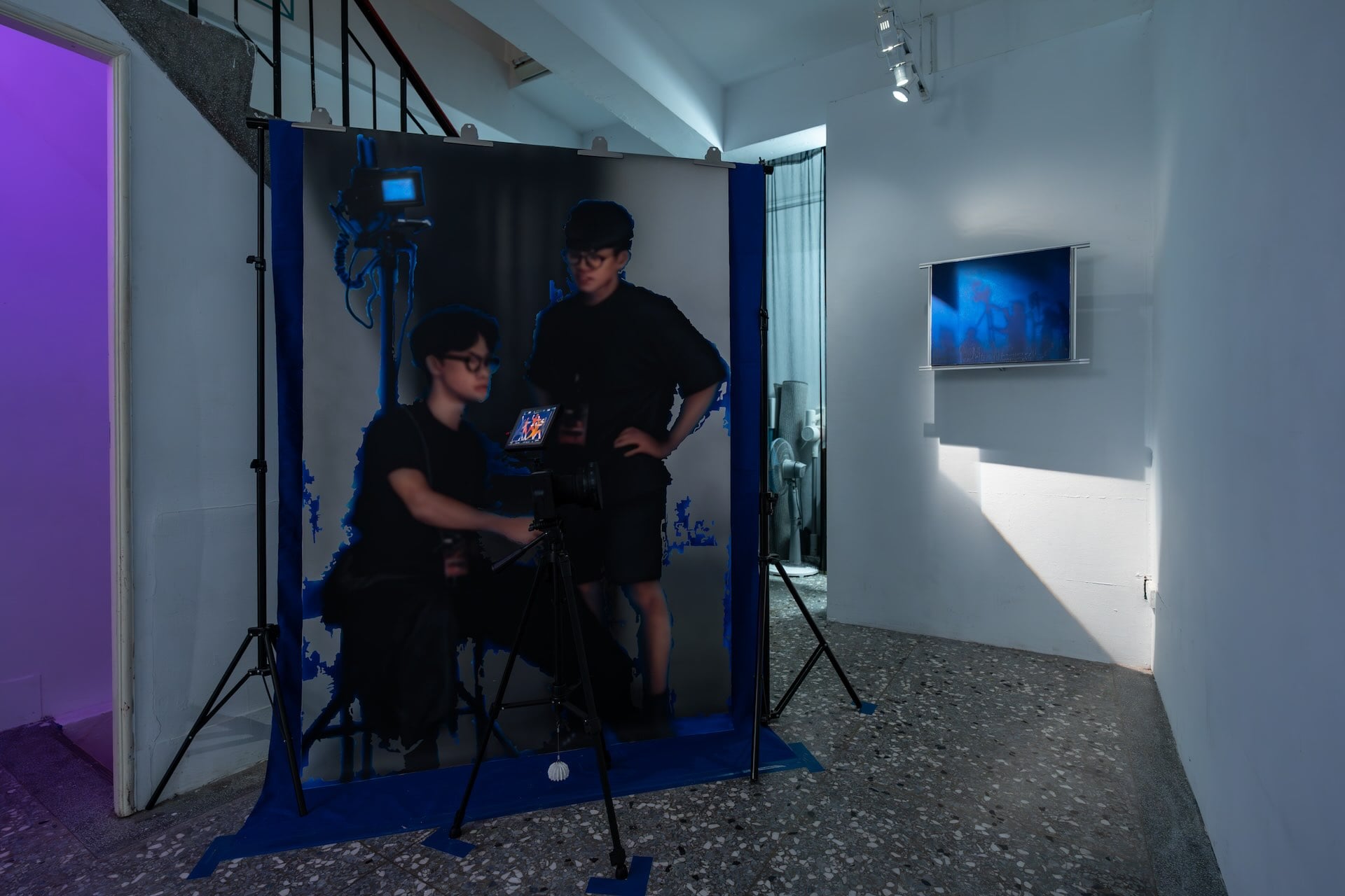 吳柏葳於私密空間展出《Chroma Set》，以藍幕劇組為靈感，搭建木造結構和攝影腳架，營造昏暗片場氛圍。畫面中也以噴漆與模糊技法描繪缺席成員陳琮皓、陳彥成的身影，使「客串成員」透過藝術方式參與展覽。（攝影／劉耀鈞，介力屋提供）